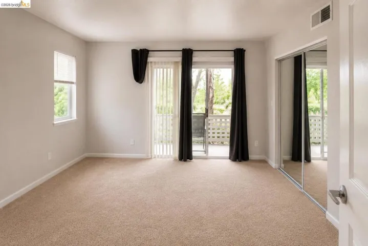 Carpeted room with a sliding glass door leading to a balcony