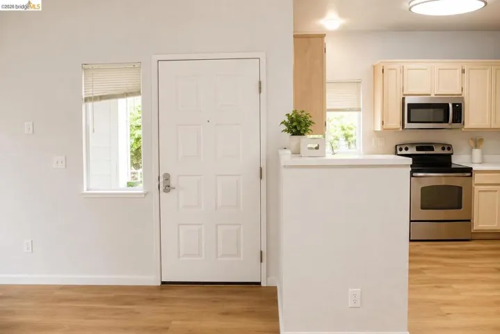 Entryway with wood-finish flooring extending into the kitchen