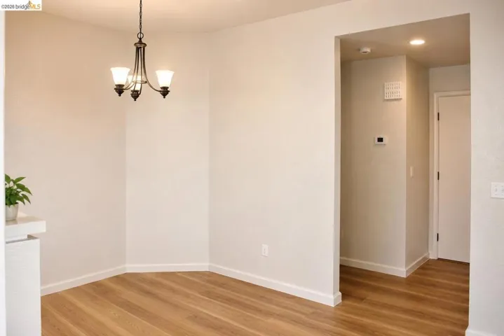 Dining space featuring wood-finish flooring, a decorative chandelier, and light-toned walls