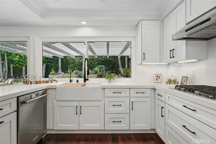 A closer look reveals a classic white farmhouse apron sink with a modern black gooseneck faucet, perfectly positioned against a white subway tile backsplash.