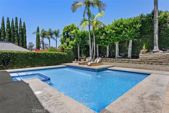 Dive into luxury with this spectacular backyard featuring a sparkling blue pool, an integrated spa, and cozy lounge chair seating.