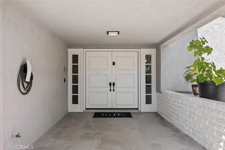 he sheltered front entry features prominent double doors flanked by sidelight windows and is conveniently equipped with a wall-mounted EV charging station.
