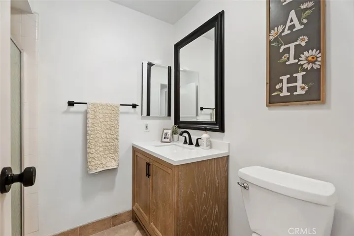 A charming main-floor bathroom complete with a rustic wood vanity, modern matte black fixtures, and clean, neutral finishes.