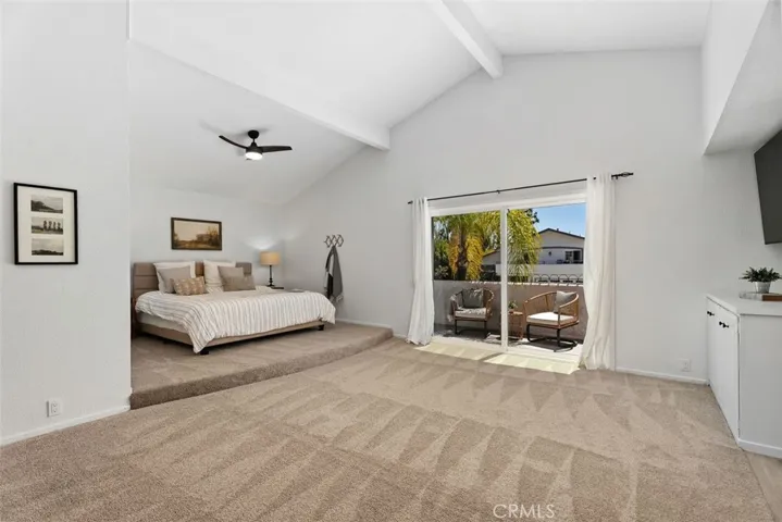 This expansive primary retreat features an elevated bed platform, high vaulted ceilings, and large sliding doors that lead out to a private balcony.