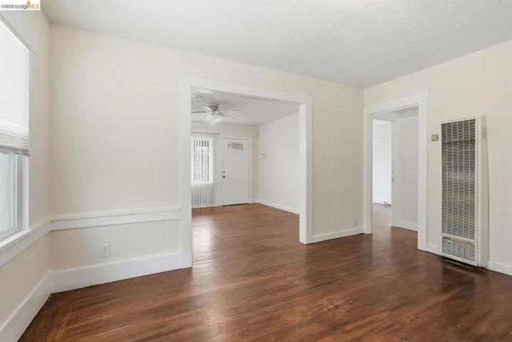 Interior space featuring rich wood-finish flooring, white walls with detailed trim, and multiple doorways