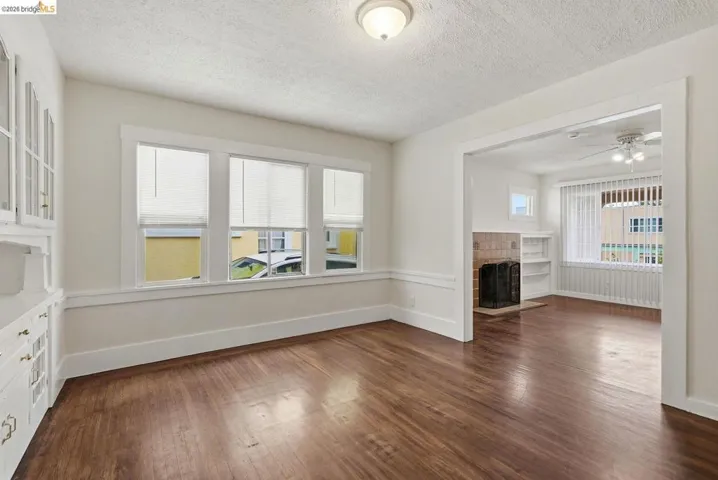 Interior space featuring wood-finish flooring, white trim, and a built-in hutch with glass-front cabinetry