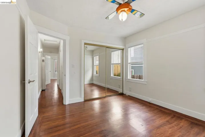 Room featuring wood-finish flooring, white walls, and a ceiling fan