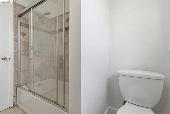 Bathroom featuring a tiled shower-over-tub with sliding glass enclosure and a white porcelain toilet
