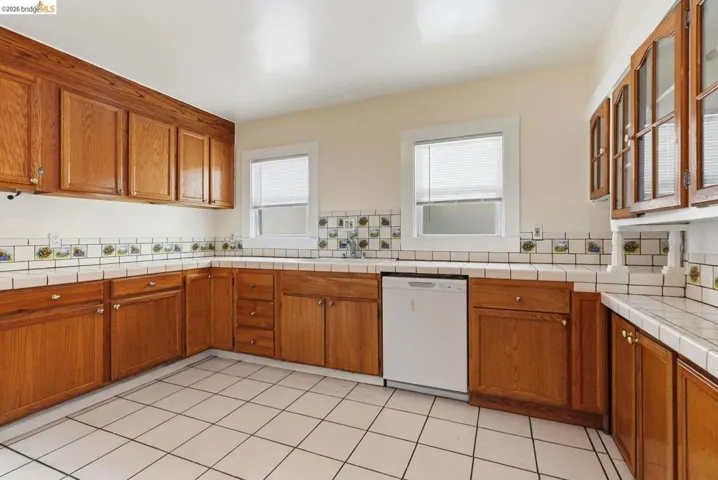 Kitchen featuring ample wood cabinetry, tiled countertops, and a white tile floor