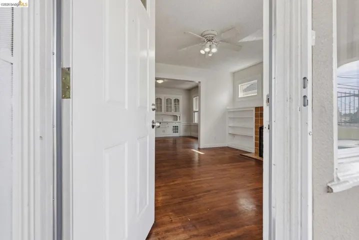 Interior features include wood-finish flooring, a white ceiling fan with integrated lighting, built-in shelving, and a tiled fireplace