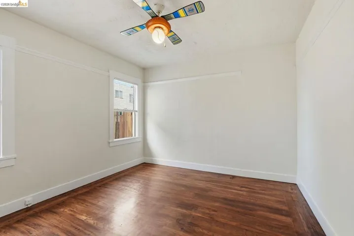 Interior room featuring wood-finish flooring, white baseboards, and a decorative ceiling fan