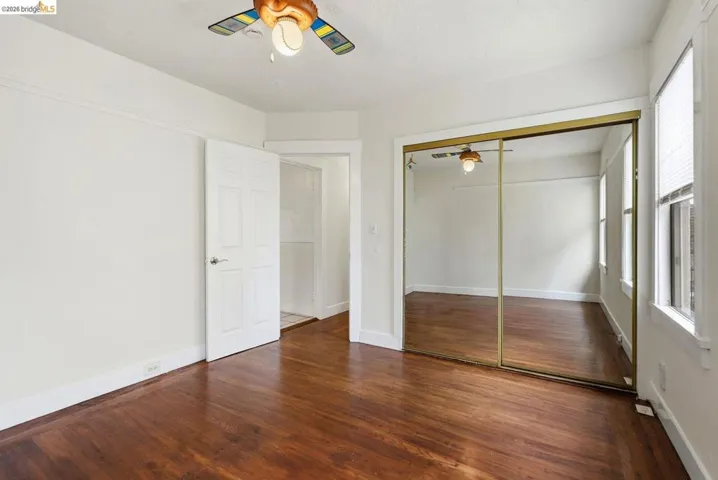 Interior room featuring wood-finish flooring, white painted walls, and a ceiling fan with integrated lighting