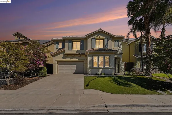 Two-story stucco residence featuring a tile roof, an integrated garage, and a concrete driveway