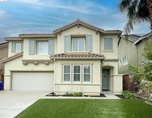 Two-story stucco residence featuring a tile roof, decorative shutters, and an attached two-car garage