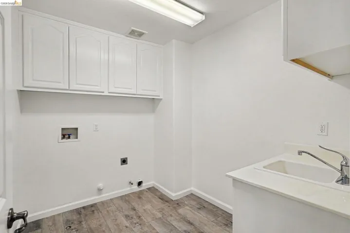 Dedicated laundry area featuring wood-finish flooring and bright white walls