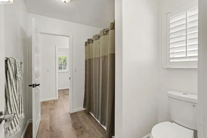 Bathroom featuring wood-finish flooring, white walls, and a white toilet