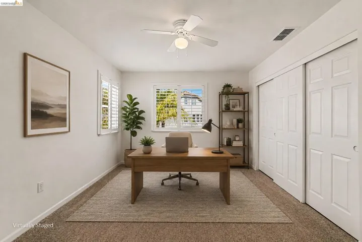 Bright room featuring two windows with white plantation shutters, a ceiling fan with integrated lighting, and a closet with bifold paneled doors