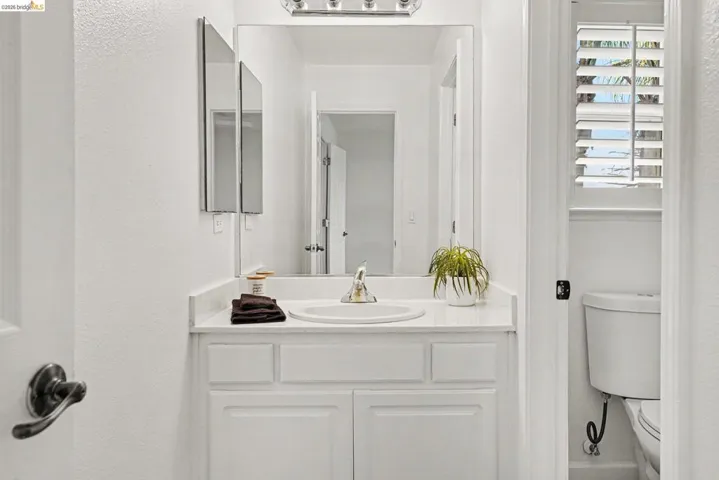 Vanity featuring an integrated sink with a chrome faucet, set within a white countertop and base cabinetry
