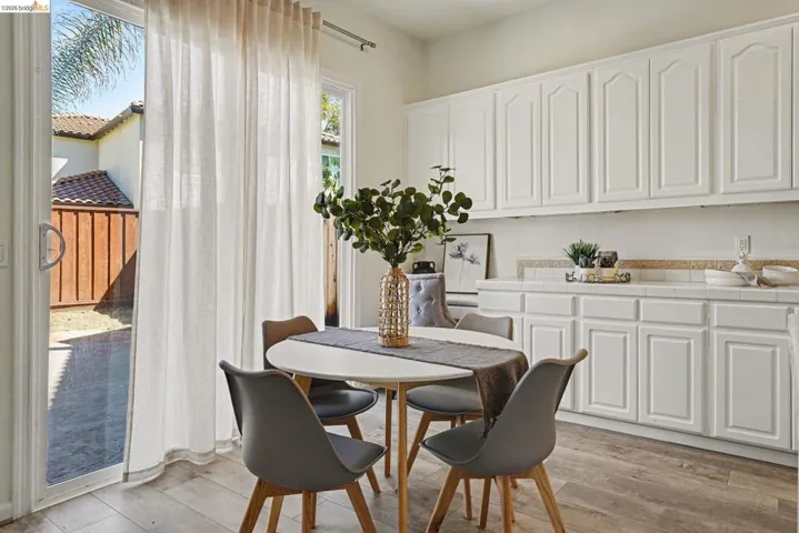 Kitchenette with white cabinetry, tile countertops, and wood-finish flooring