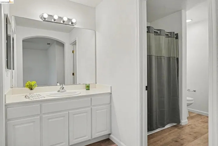 Bathroom featuring a vanity with an integrated sink, white cabinetry, and a wide mirror