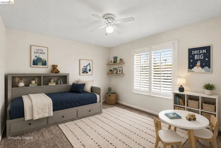 Bright interior space featuring a window with white plantation shutters, neutral wall tones, and overhead ceiling fan lighting