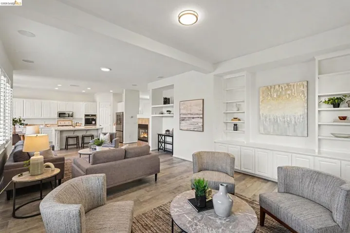 Spacious living area featuring light wood-finish flooring, recessed lighting, and integrated wall shelving with base cabinetry