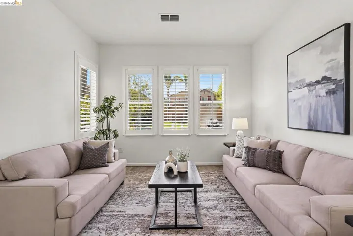 Living area featuring white walls, three windows with plantation shutters, recessed lighting, and wood-finish flooring