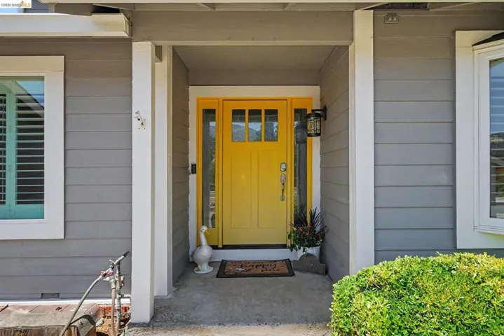 Inviting yellow front door with sidelights, set within a covered entry
