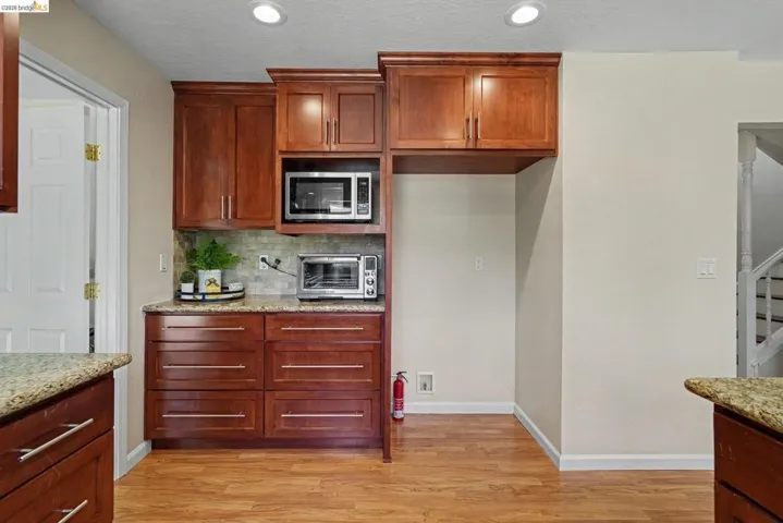 Kitchen area featuring rich wood cabinetry, granite-finish countertops, and wood-finish flooring