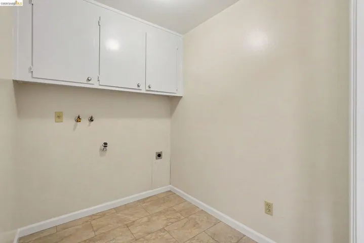 Laundry area featuring overhead cabinetry, tile flooring, and utility hookups