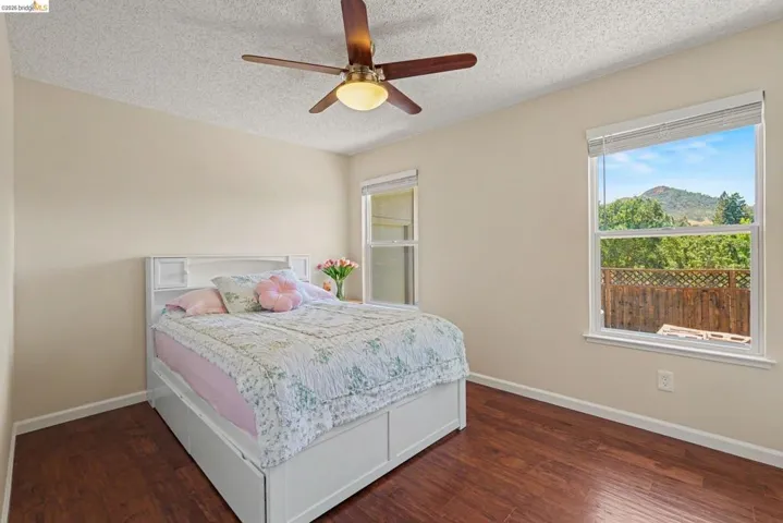 Bedroom featuring wood-finish flooring, a ceiling fan with integrated lighting, and neutral wall tones