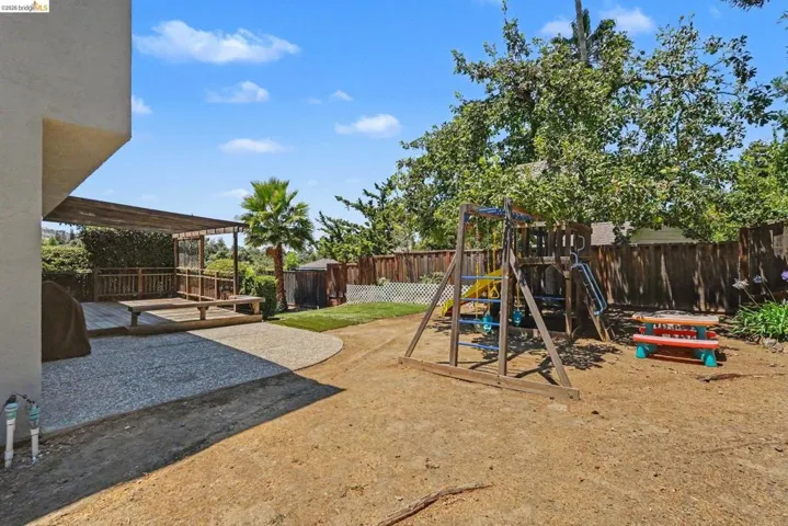 Expansive outdoor space featuring a covered wood deck, a partial gravel patio, and a grass area