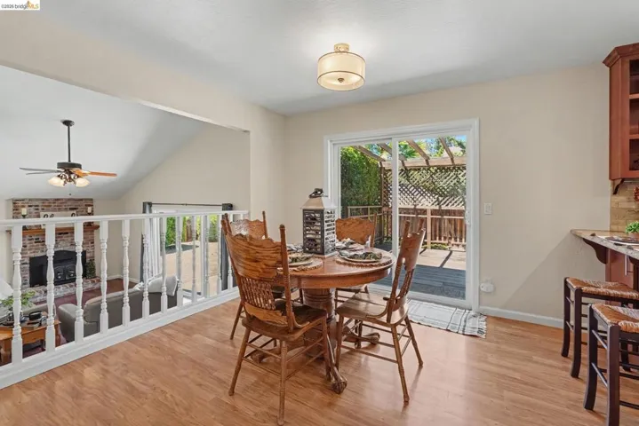 Dining area featuring wood-finish flooring, a contemporary ceiling light fixture, and a sliding glass door providing access to an outdoor deck with a pergola