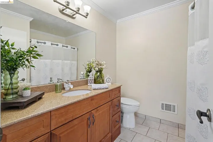 Bathroom vanity featuring a light-toned stone countertop, integrated sink, and wood-finish cabinetry with dark hardware