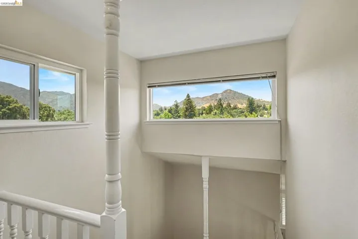 Stairwell featuring white painted balusters and railings, two windows, and a mountain landscape backdrop