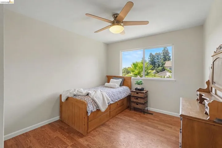 Light-filled room featuring wood-finish flooring, a ceiling fan with integrated lighting, and a window offering natural light