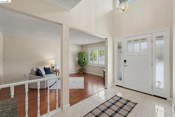 Entryway featuring a high ceiling, a multi-paneled white front door with side lites, and light-toned tile flooring