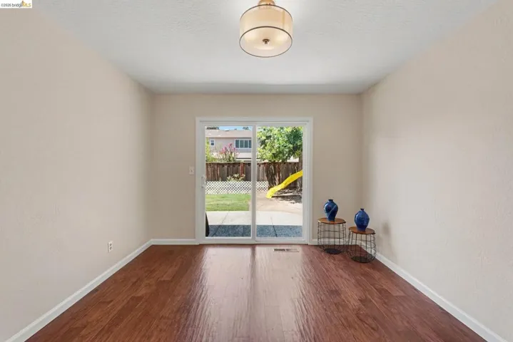 Wood-finish flooring throughout, featuring a drum pendant light fixture and sliding glass doors to the outdoor space