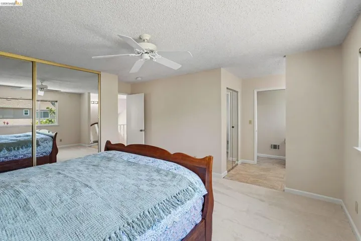 Bedroom featuring neutral wall colors, carpeting, a ceiling fan, and mirrored closet doors