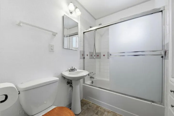 Bathroom with pedestal sink and shower over tub.