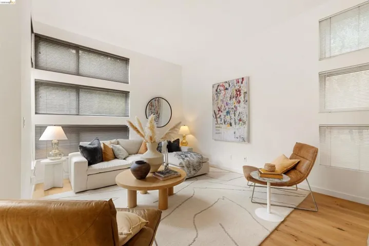 Living area featuring high ceilings, wood-finish flooring, and multiple horizontal windows