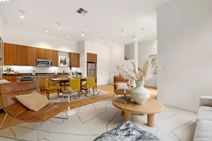 Open-concept living space featuring wood-finish flooring, a kitchen with full-height wood cabinetry and stainless steel appliances, and integrated recessed lighting
