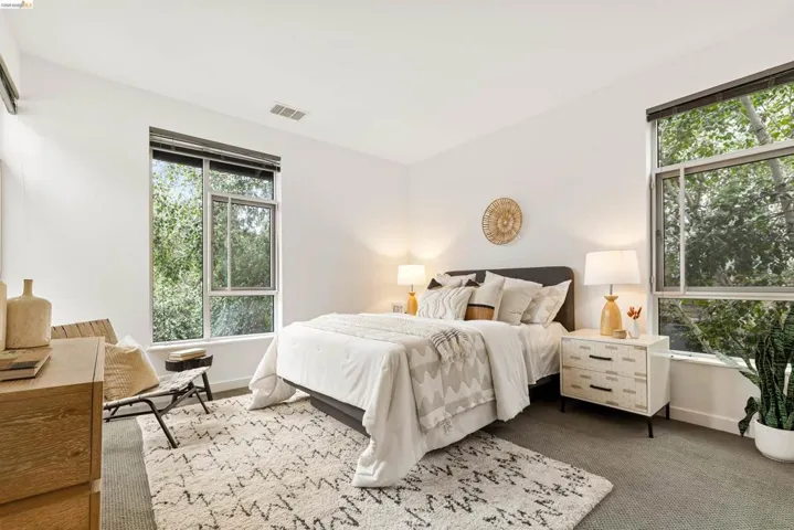 Bright interior featuring large windows, light gray carpeting, crisp white walls, and a recessed air conditioning unit
