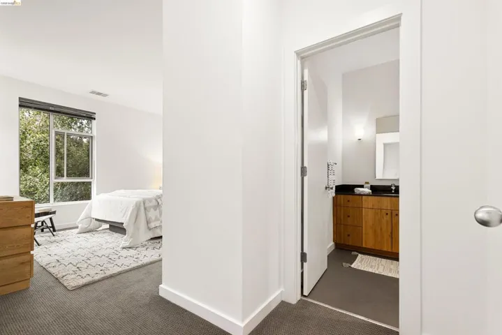 Bedroom with large window overlooking exterior foliage, wall-to-wall carpeting, and bright white walls