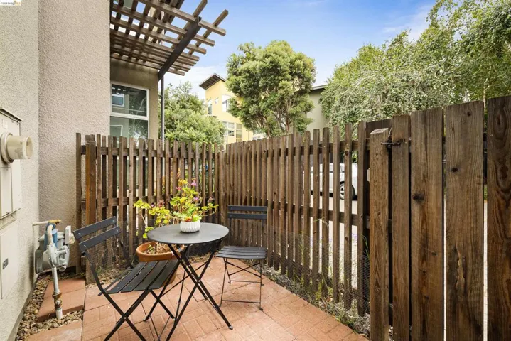 Private patio space featuring brick paver flooring, a wooden slatted privacy fence, and an overhead wooden pergola structure