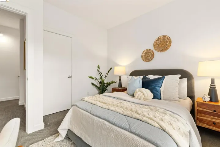 Bedroom featuring a textured upholstered headboard, clean white walls, and soft gray carpeting