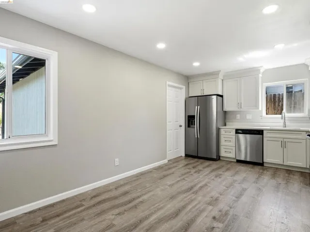 Kitchen area featuring white shaker-style cabinetry with crown molding, stainless steel appliances, and a undermount sink