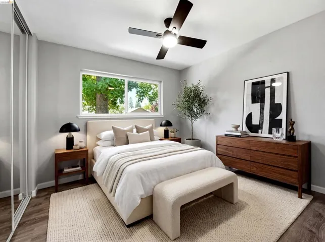 Bright bedroom featuring a contemporary ceiling fan with integrated lighting, wood-finish flooring, and a window with exterior views