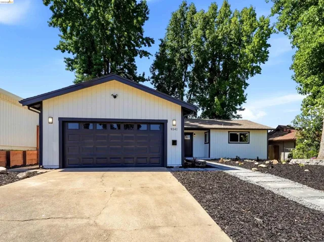 Contemporary exterior with white siding and dark trim, featuring a two-car garage with a panel door and transom windows