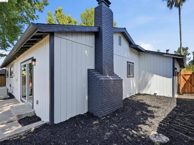 Crisp white vertical siding exterior with contrasting dark trim and a prominent dark brick chimney